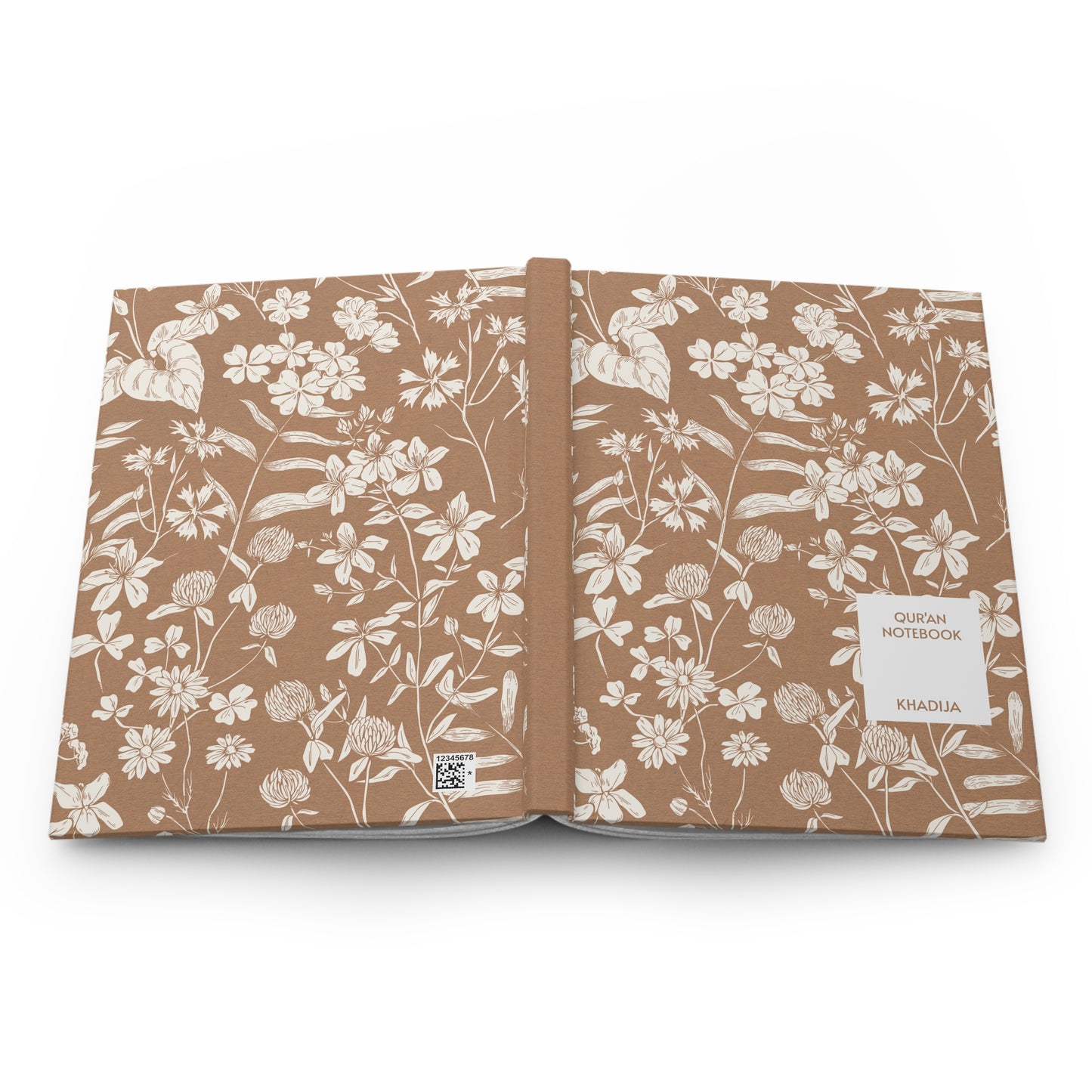 Full product view of a Quran notebook with white floral art on a brown background.